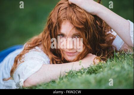 Junge Frau liegt auf dem Rasen Stockfoto