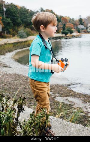 Kleiner Junge am See stehen, halten Ferngläser Stockfoto