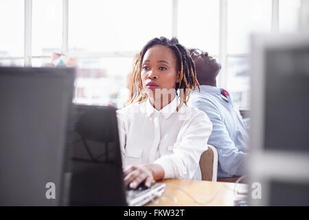 Kolleginnen und Kollegen im Fice am Computer auf der Suche überarbeitet Stockfoto