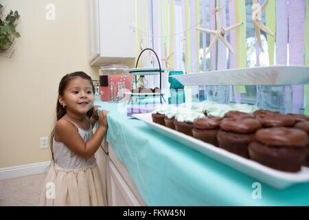 Junges Mädchen Blick sehnsüchtig auf Kuchen Küche Arbeitsplatte Stockfoto