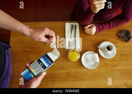 Overhead beschnitten Ansicht Kellner entfernen nach Erhalt von Kreditkarten-Maschine im restaurant Stockfoto