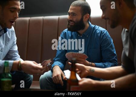 Drei junge Erwachsene männliche Freunde Spielkarte Spiel im traditionellen UK pub Stockfoto