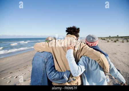 Drei Freunde Strand entlang, Arme umeinander, Rückansicht Stockfoto