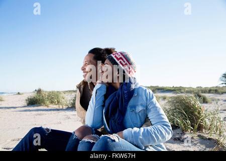 Junges Paar sitzt am Strand, betrachten Stockfoto