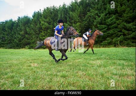 Seitenansicht der Mädchen und Reife Frau im Galopp auf dem Pferd Reiten-Hüte tragen Stockfoto