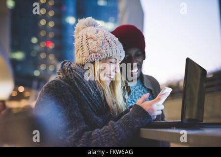 Paar mit Smartphone und Laptop im Freien in der Abenddämmerung Stockfoto