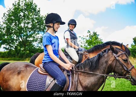 Seitenansicht der Reife Frau und Mädchen auf Pferde tragen Reiten Hüte lächelnd Stockfoto