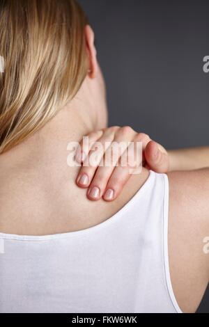 Schuss von jungen Womans Hand massieren ihre eigene Schulter hautnah abgeschnitten Stockfoto