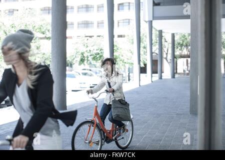 Zwei Freundinnen mit Überseerennen Haar Radfahren in der Stadt Stockfoto