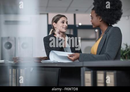 Zwei junge Unternehmerinnen im Gespräch an der Rezeption Büro Stockfoto