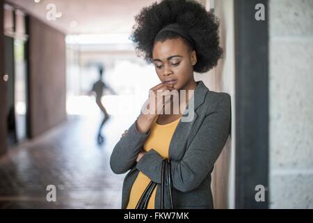 Junge Unternehmerinnen mit Hand am Kinn Büro an der Wand gelehnt Stockfoto