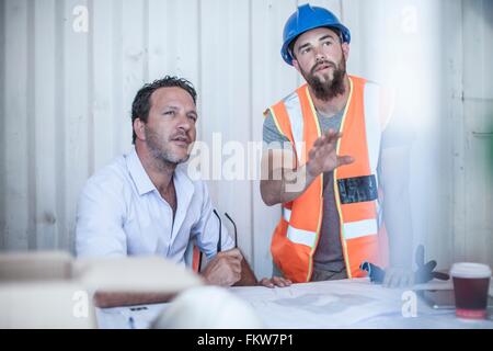 Arbeiter und Bau Vorarbeiter treffen am Schreibtisch in tragbaren Kabine Stockfoto