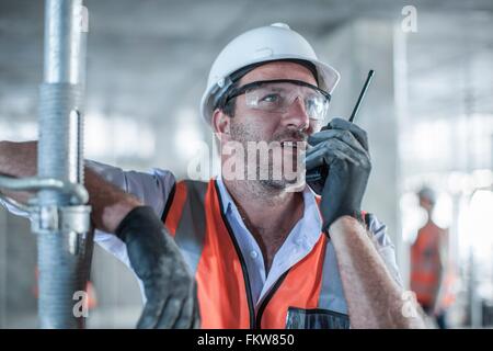 Mitte erwachsenen männlichen Bauleiter mit Walkie-Talkie auf Baustelle Stockfoto