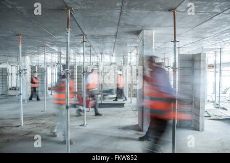 Sechs verschwommene Bauarbeiter im geschäftigen Baustelle unterwegs Stockfoto