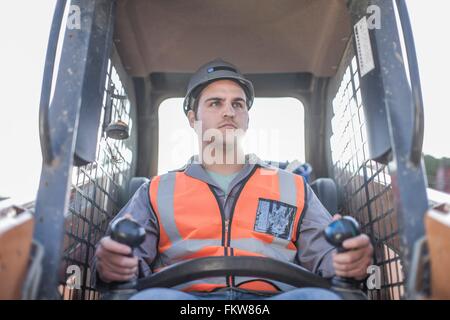 Junger Mann fahren Bagger auf der Baustelle Stockfoto