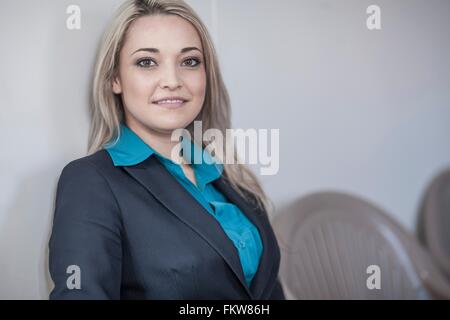 Porträt der jungen Unternehmerin mit langen blonden Haaren, die im Büro sitzen Stockfoto