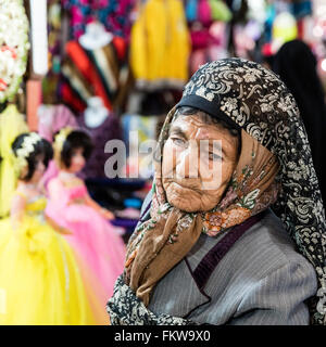 Ältere Frau Hijab steht vor einem Vakil Bazar Stall an dem Puppen verkauft werden. Shiraz, Iran Stockfoto