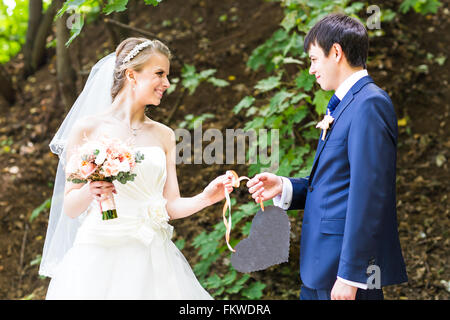 Braut und Bräutigam mit einem Schild in Herzform. Stockfoto