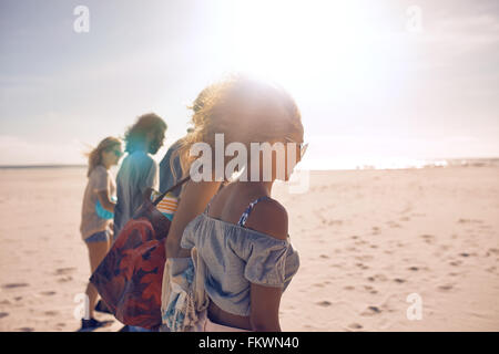 Aufnahme einer Gruppe von jungen Freunden an einem sonnigen Tag am Strand entlang spazieren. Männer und Frauen, die Sommer-Urlaub am Strand. Stockfoto