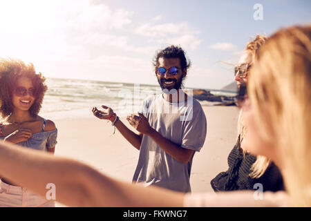 Heterogene Gruppe von Jugendlichen stehen zusammen und reden. Freunde, die sich an einem sonnigen Tag am Strand zu genießen. Stockfoto