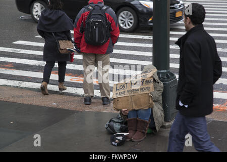 Person greift nach Hilfe mit einem Schild, wie der ständige Fluss von Fußgängern passieren auf 42nd St. & 5th Ave. In NYC Stockfoto