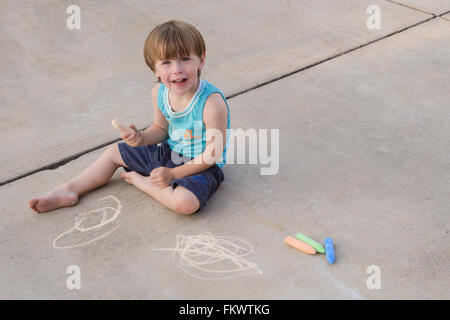 Ein dreijährige Bürgersteig Kreide Künstler sitzt auf einem hellen farbigen Pflaster. Platz an der Seite für Text kopieren. Stockfoto