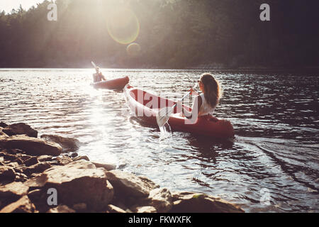 Junge Menschen in einem See paddeln. Junger Mann und Frau Kajaks paddeln, an einem sonnigen Tag. Stockfoto