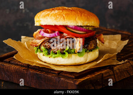 Burger mit Fleisch und Speck auf dunklem Hintergrund Stockfoto