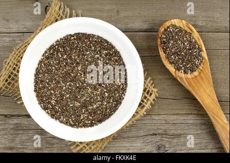 Schüssel und Löffel gefüllt mit Chiasamen über einen Holz Hintergrund Stockfoto