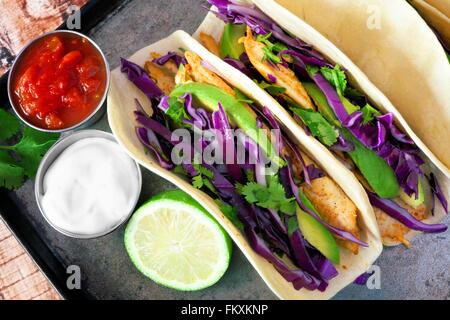 Würziger Fischtacos mit Rotkohl Krautsalat, Avocado und Limettensaft, Draufsicht auf Vintage Tablett Stockfoto