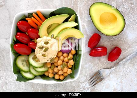 Gesunde Ernährung Schüssel mit Avocado, Hummus und Mischgemüse, obenliegende Szene auf weißem Marmor Stockfoto