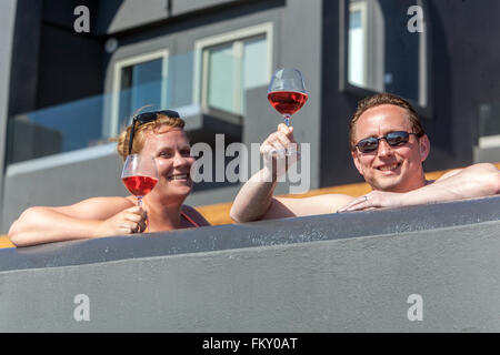 Gäste des Hotels trinken Rotwein auf der Terrasse und sonnen sich ihre Körper, Santorini, Griechenland Touristen genießen den Komfort der Terrassenmenschen auf der Terrasse Stockfoto