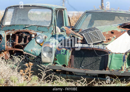 Verlassene und verrostete Wracks eines Mercedes-Benz W115 und eines Lastwagens auf den griechischen Inseln. Umweltmüllbewirtschaftung und soziale Verwirrung Stockfoto