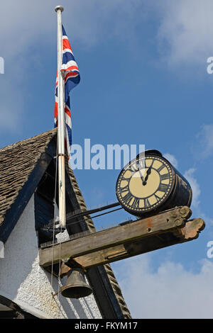 Alte Uhr und britischen Union Jack-Flagge am Gebäude in Burford, Oxfordshire, England Stockfoto