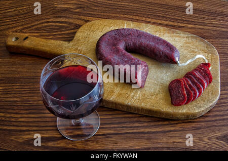 Glas Rotwein und in Scheiben geschnittenen bulgarischen Salami auf einem Holzbrett Stockfoto