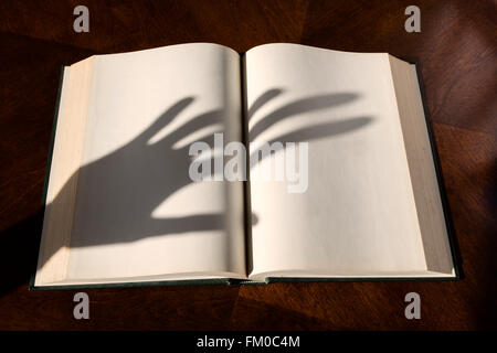 Leere weiße Seiten in ein offenes Hardcover Buch und Schatten der hand Stockfoto