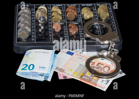 Handschellen, Euro-Scheine und Organisator der Euro-Münzen auf schwarzem Hintergrund Stockfoto