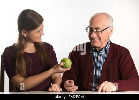 junge Frau hilft senior woman, grünen Apfel zu essen Stockfoto