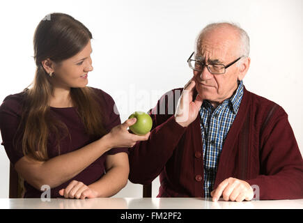 junge Frau hilft senior woman, grünen Apfel zu essen Stockfoto