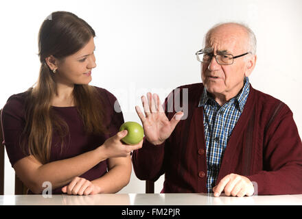 junge Frau hilft senior woman, grünen Apfel zu essen Stockfoto