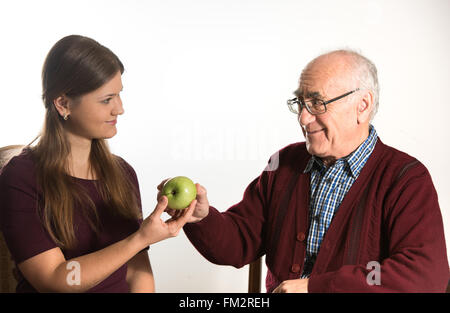 junge Frau hilft senior woman, grünen Apfel zu essen Stockfoto