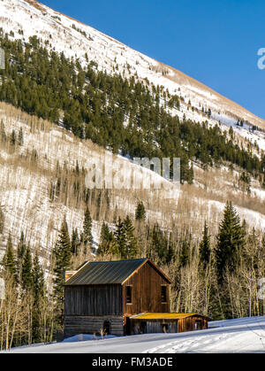 Verlassenes Holzhaus vor einem Berg im winter Stockfoto