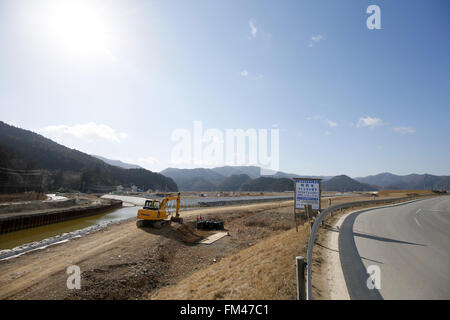 Deiche das Baugewerbe in der Nähe der Überreste der Okawa Elementary School am 11. März 2016 in Ishinomaki, Präfektur Miyagi, Japan. Genau 5 Jahre früheren 74 aus 108 Schüler verloren ihr Leben durch den Tsunami am 11. März 2011. Gibt es Pläne zum Wiederaufbau der Schulhaus, aber bisher hat dies nicht behoben. Das Schicksal der zerstörten Gebäude soll auch bald mit den Bewohnern der Stadt geteilt, ob sie als Mahnmal erhalten oder entfernt werden sollte entschieden werden. © Yusuke Nakanishi/AFLO/Alamy Live-Nachrichten Stockfoto