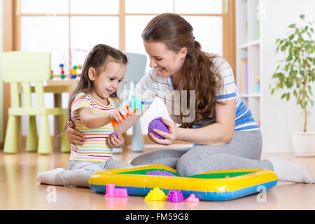 Kind Mädchen und Mutter spielen mit kinetischen sand zu Hause Stockfoto