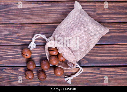 Macadamia-Nüssen in Beutel und auf einem Tisch Stockfoto