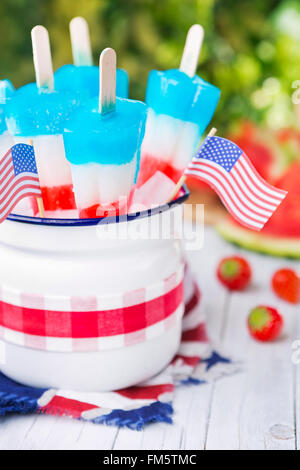 Hausgemachte rot-weiß-blauen Eis am Stiel auf einen Tisch im Freien mit erfrischenden Limonade im Hintergrund. Stockfoto