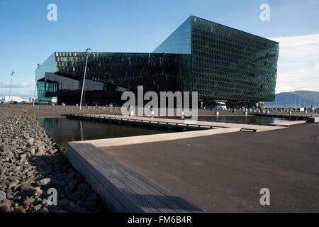 Ein großes, modernes Gebäude in Island, das den Harpa Konzertsaal, Reykjavik, mit einer Rampe zum Haupteingang über Wasser. Stockfoto