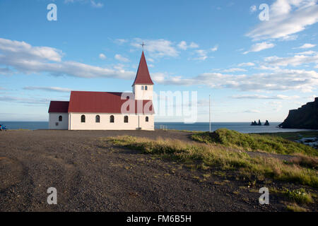 Im Hintergrund sind eine alte Kirche mit Blick auf Vik, in Island, das Meer und die großen Berge zu sehen. Stockfoto