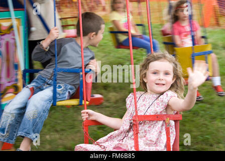 TEWKESBURY, GLOS. UK - Juli 2013: Kleines Mädchen winken aus dem Karussell am 13. Juli 2014 bei Tewkesbury Mittelalterfest Stockfoto