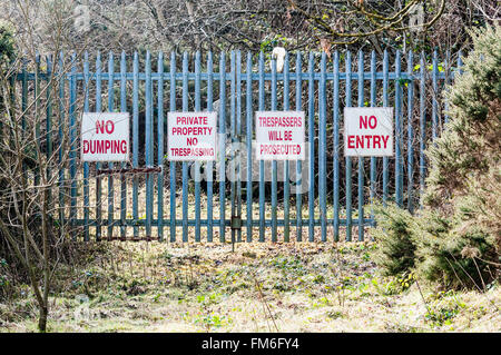 Zeichen auf einem Sicherheitstor Warnung "No Dumping", "Private Property, No Trespassing", "Eindringlinge werden strafrechtlich verfolgt", "No Entry" Stockfoto